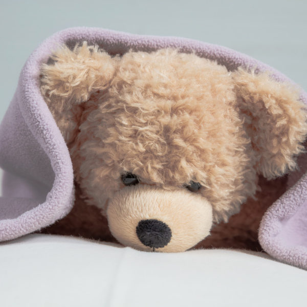 Kids bedtime, baby shower. Cute teddy laying on bed mattress covered with a towel